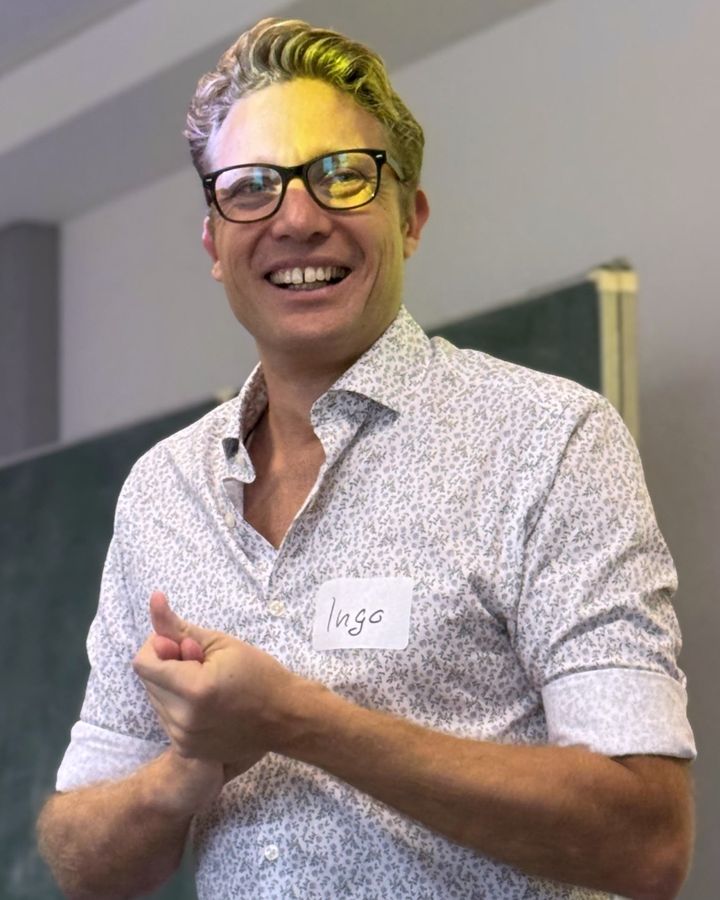 Ingo Schönleber, smiling, in front of a blackboard during a workshop